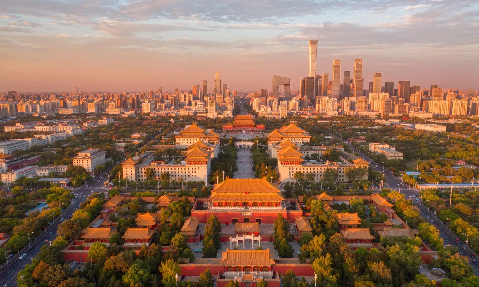 Beijing's Forbidden City rooftops with the modern CBD skyline in the distance at dusk