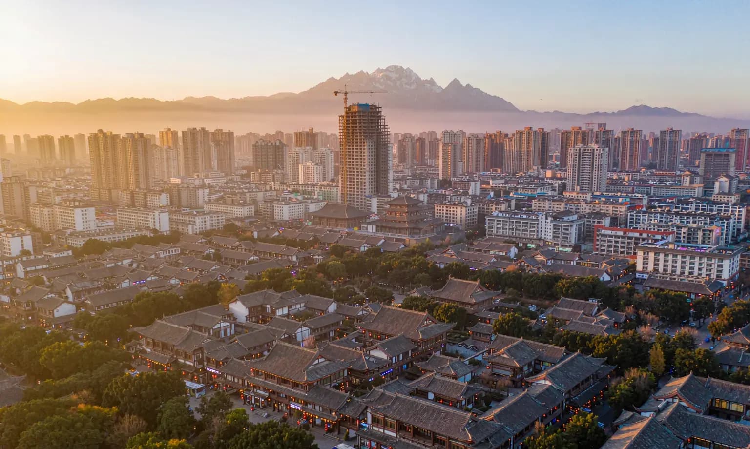 Lantern-lit teahouse rooftops in Chengdu with the city skyline and distant mountains
